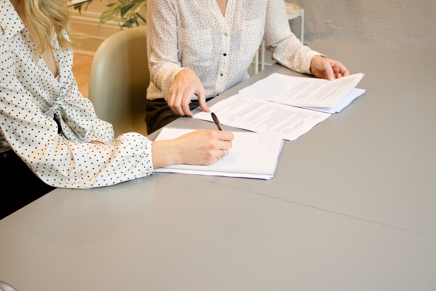 A person signing paperwork at a desk